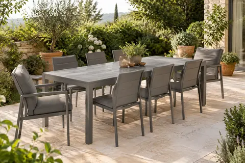 Table extensible en aluminium avec six chaises et deux fauteuils en textilène dans une terrasse végétalisée