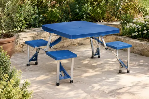 Table de camping bleue avec quatre places intégrées, installée sur une terrasse de jardin végétalisée