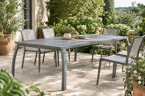 Table de jardin extensible Devoko en aluminium gris, installée en format long sur une terrasse végétalisée.