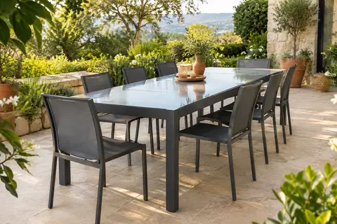 Table de jardin extensible graphite avec plateau en verre trempé, installée sur une terrasse végétalisée.