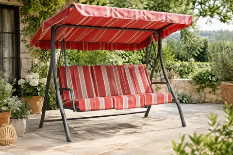 Balancelle de jardin à rayures rouges, avec coussins et toit inclinable, installée sur une terrasse végétalisée.