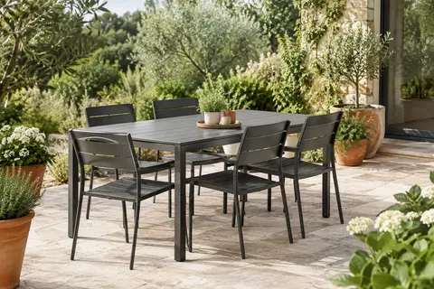 Table de jardin en acier gris foncé entourée de six chaises sur une terrasse végétalisée