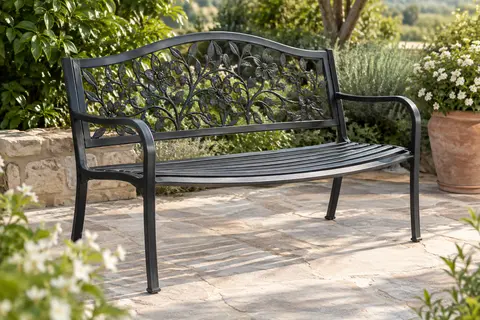 Banc de jardin noir en métal avec dossier en fonte orné d’un motif floral, installé sur une terrasse végétalisée.
