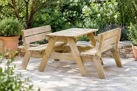 Table pique-nique Pinolino en bois naturel avec deux bancs et dossier, installée dans un jardin verdoyant.