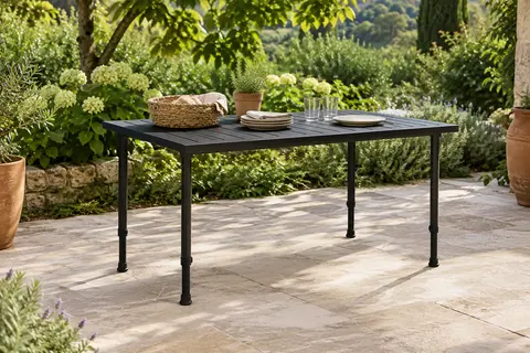 Table pliante noire en aluminium installée sur une terrasse de jardin, avec ses pieds réglables déployés.