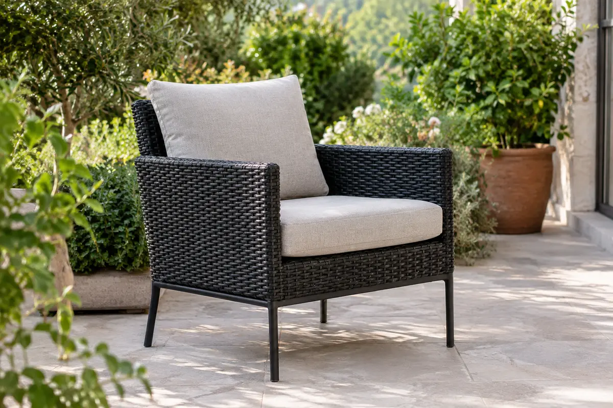 Fauteuil de jardin en polyrotin noir avec accoudoirs et coussins, installé sur une terrasse végétalisée