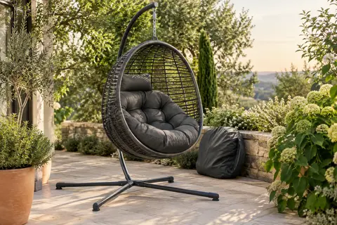 Fauteuil suspendu gris anthracite avec support en acier et coussin épais sur une terrasse végétalisée