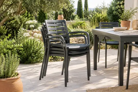 Quatre chaises de jardin anthracite avec accoudoirs, dont certaines empilées près d’une table de terrasse
